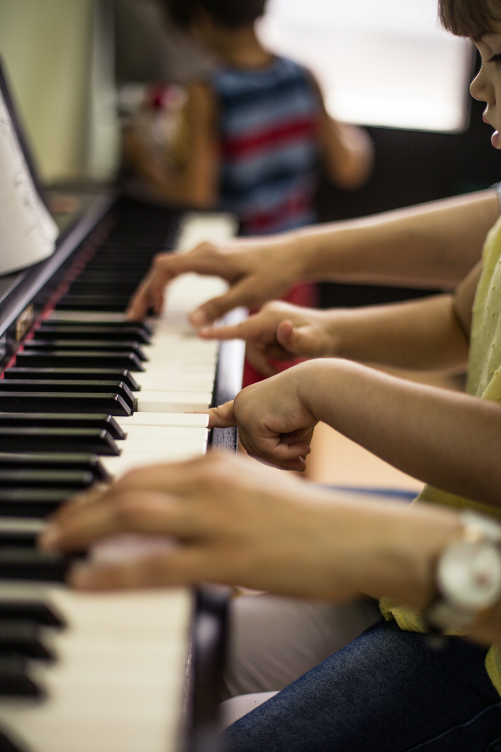 Children's hands playing a piano keyboard together