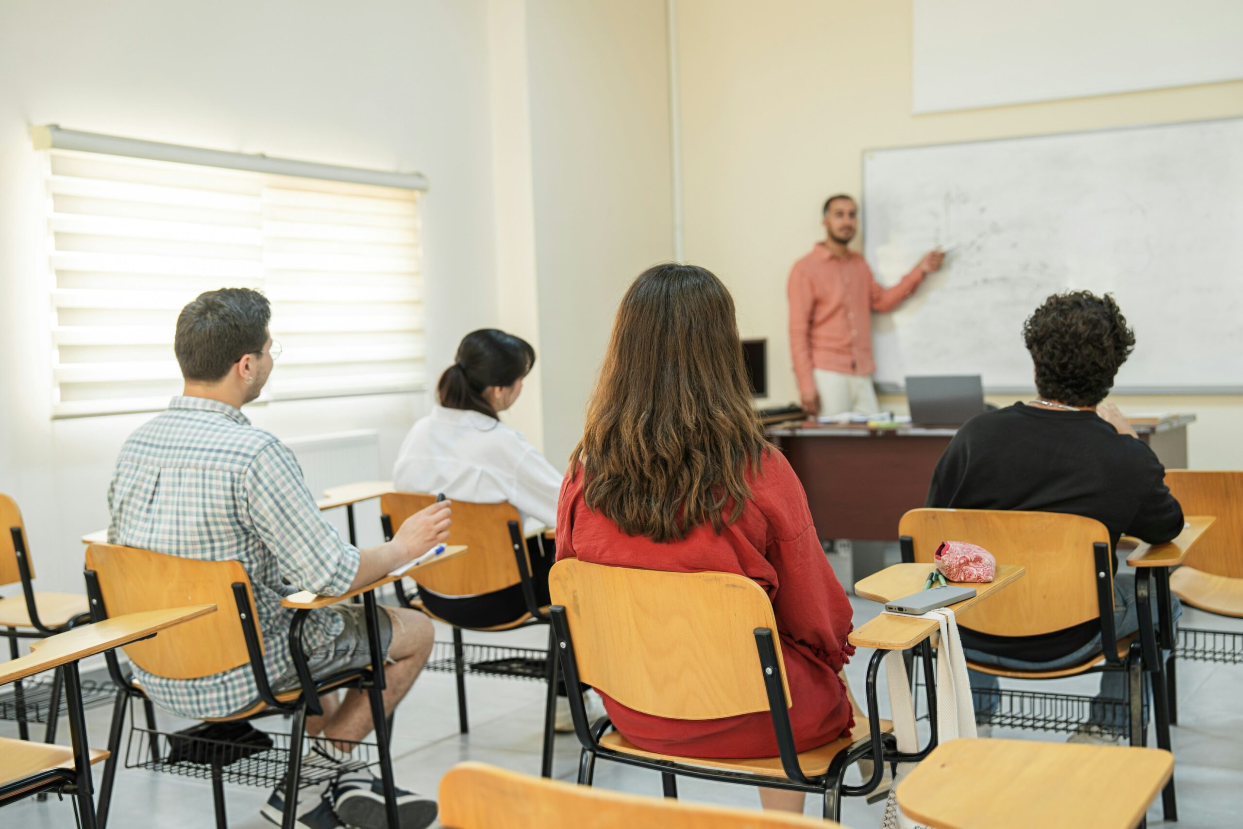 Teacher at the whiteboard leading a lesson for a small group of adult learners