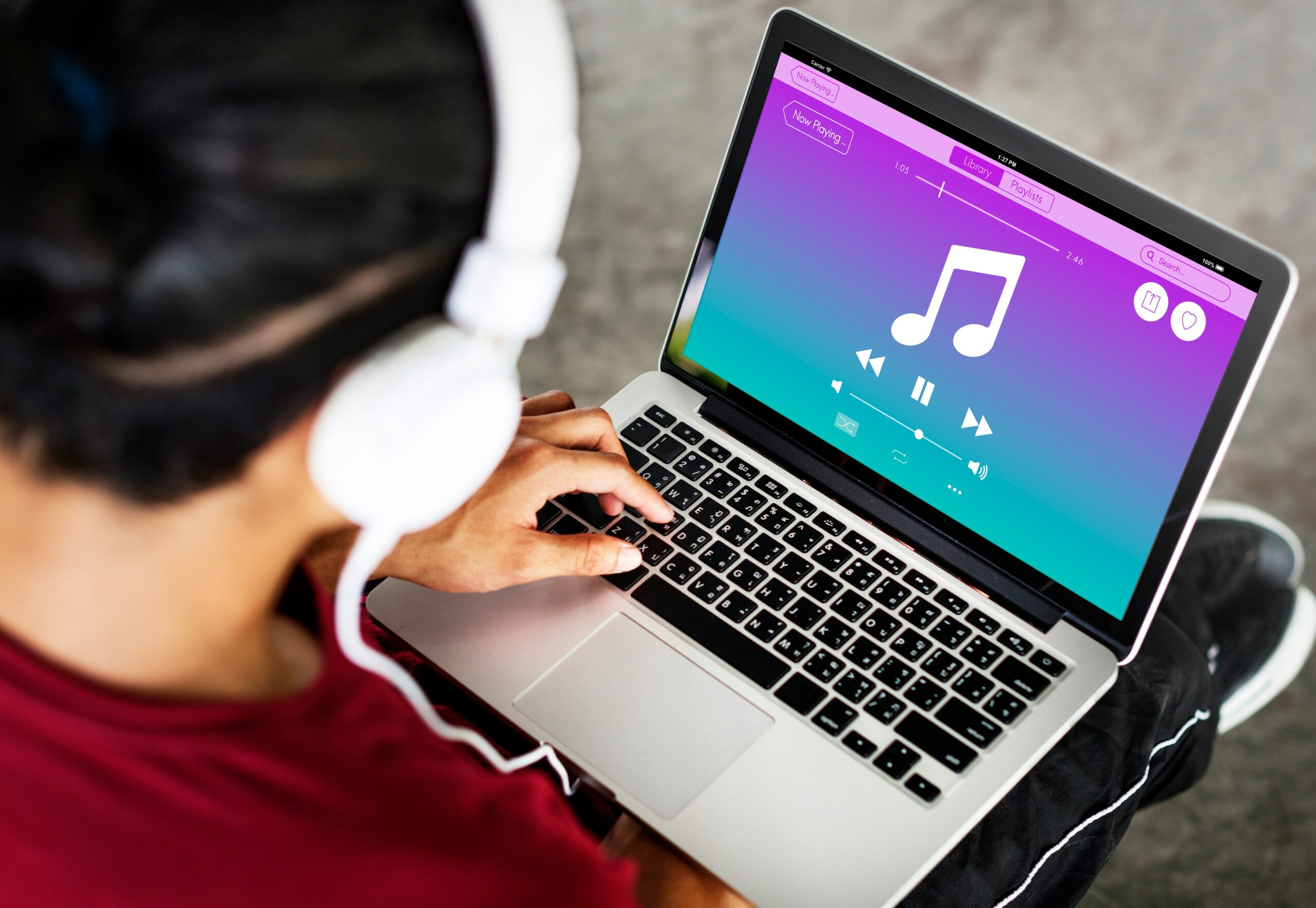 Student with headphones using a music app on a laptop