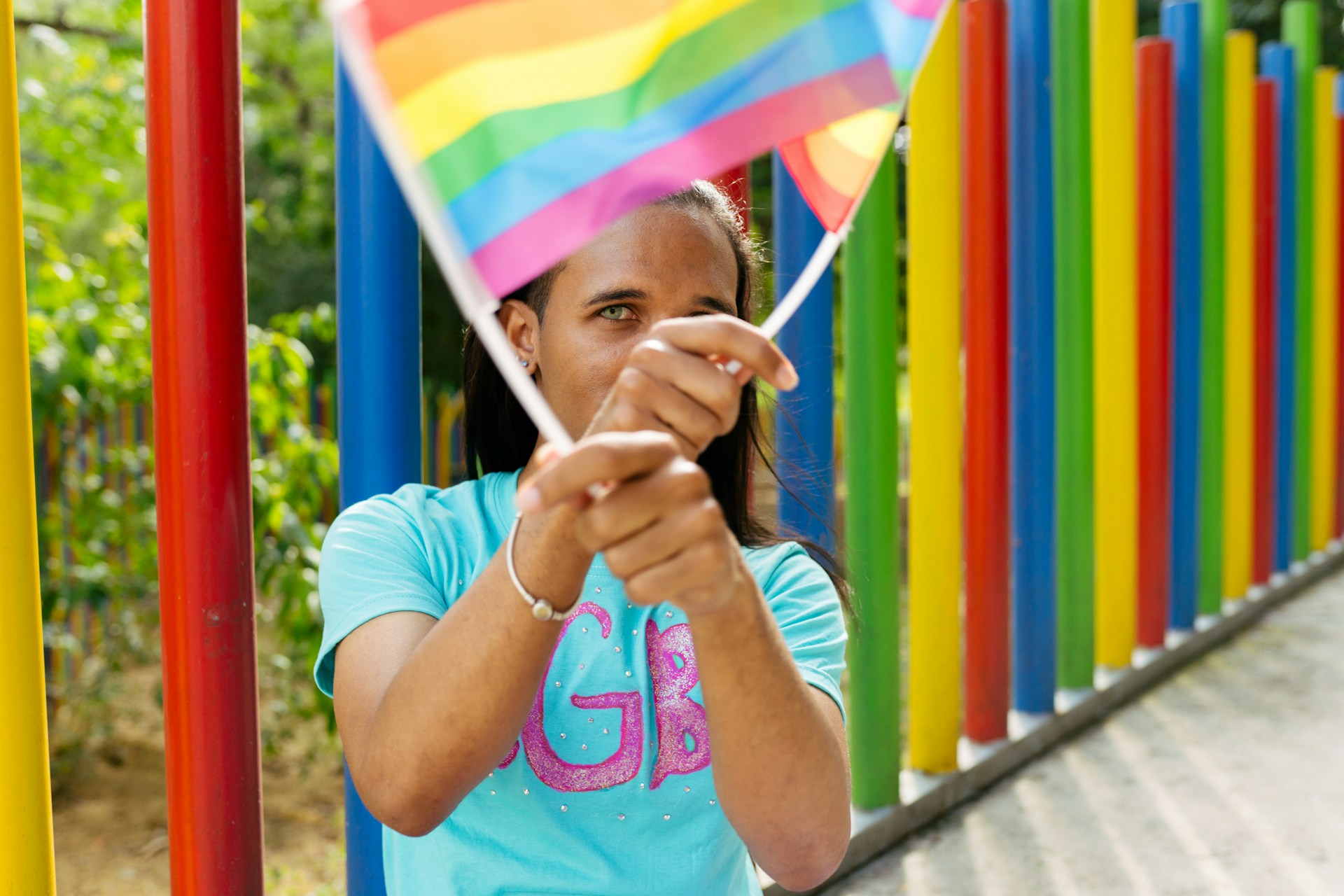 Young woman waving rainbow flags among colorful poles