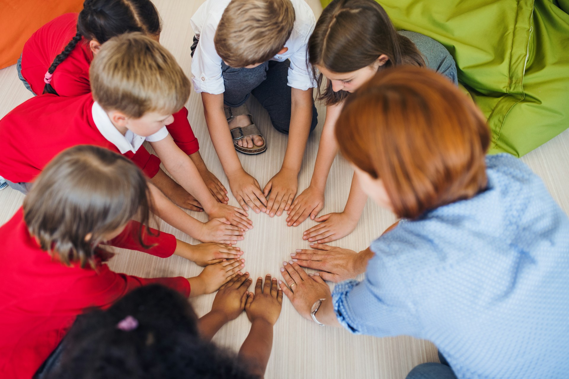 Teacher and children putting their hands together in a circle