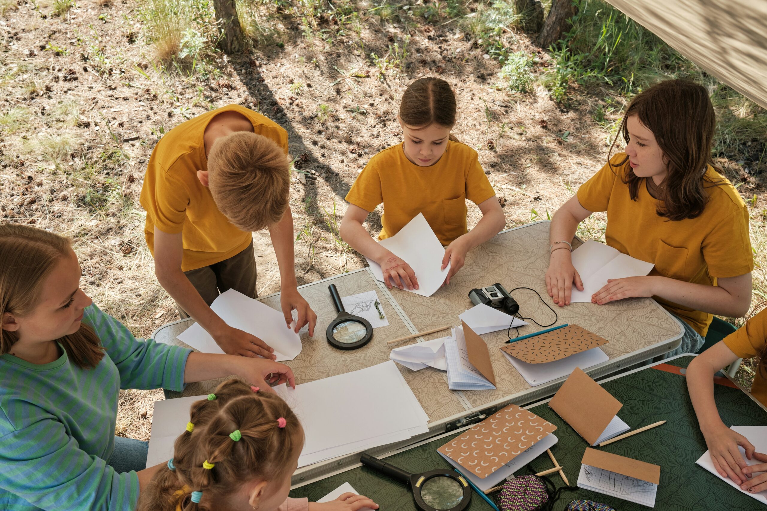 Children in yellow T-shirts doing hands-on activities at an outdoor table
