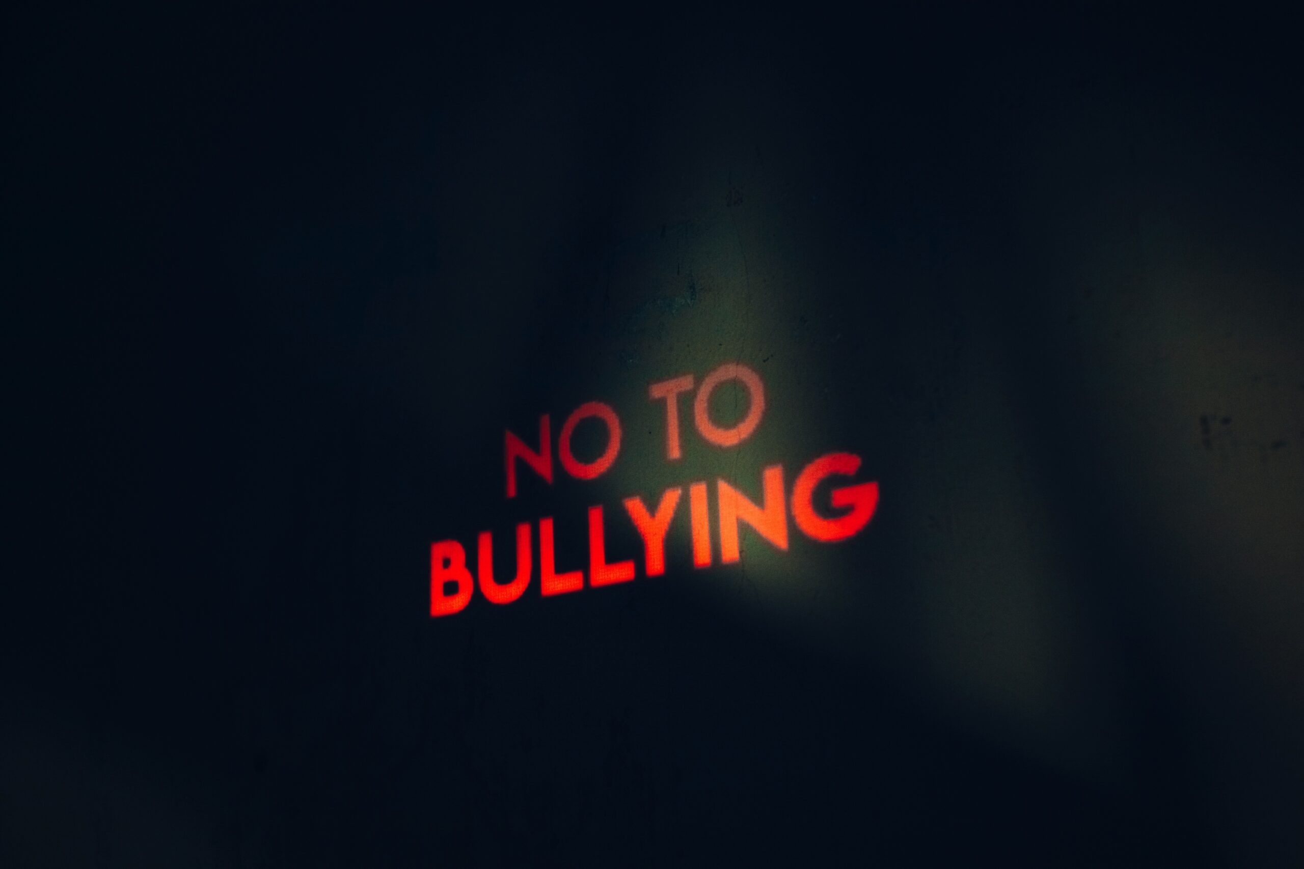 Red neon sign reading No to bullying on a dark background