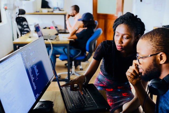 Two young people working together at a computer in a shared workspace