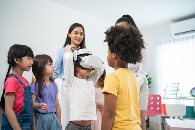 Children in a classroom trying a virtual reality headset with their teacher